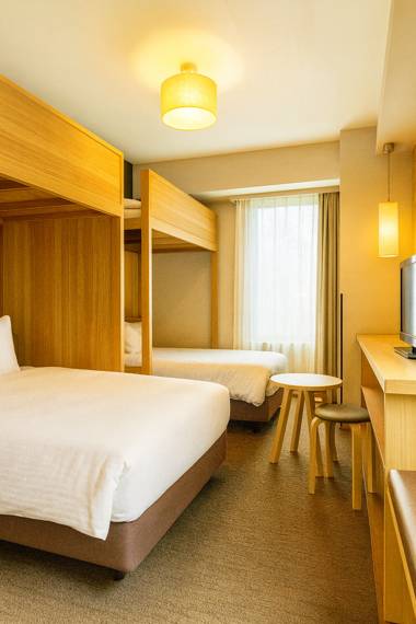 후쿠오카 숙소 호텔 리솔 트리니티 하카타 객실 내부, 따뜻한 조명과 원목 인테리어로 아늑한 분위기를 주는 침실 전경