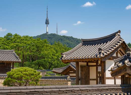 Beautiful autumn view of Namsangol Hanok Village in Seoul, showing traditional Korean wooden houses with tiled roofs under a clear blue sky