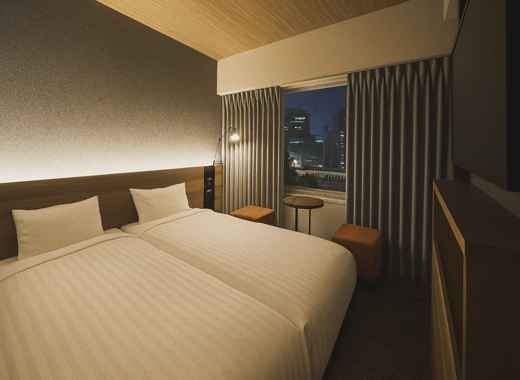 Twin room at Rihga Place Higobashi Osaka with warm lighting and city night view
