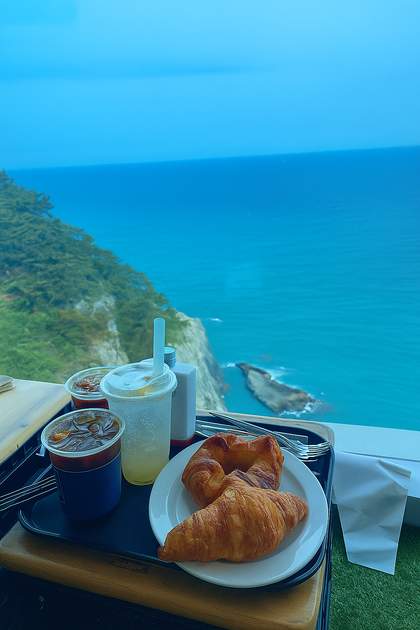 Croissant and iced drinks served at Blue Bean Café, a seaside Busan cafe with a panoramic ocean view from a cliffside window
