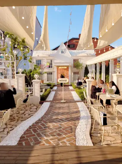 Outdoor terrace of M.mooni Cafe near Apgujeong Rodeo Street restaurants, featuring warm sunset lighting and a charming garden walkway.