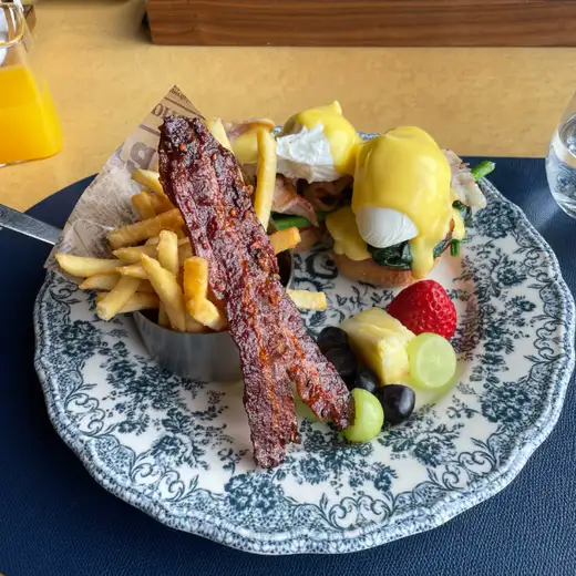 Breakfast plate at Bayhill Pool & Villa in Jeju with eggs benedict, fries, candied bacon and fresh fruits