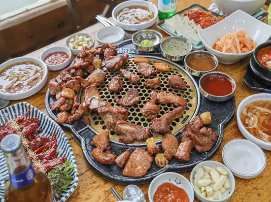 Korean BBQ pork ribs and side dishes served after a Buk Seoul Dream Forest travel course, featuring grilled galbi and traditional Korean banchan.