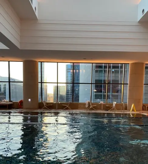 Conrad Seoul indoor swimming pool with city view through large windows and warm ambient lighting