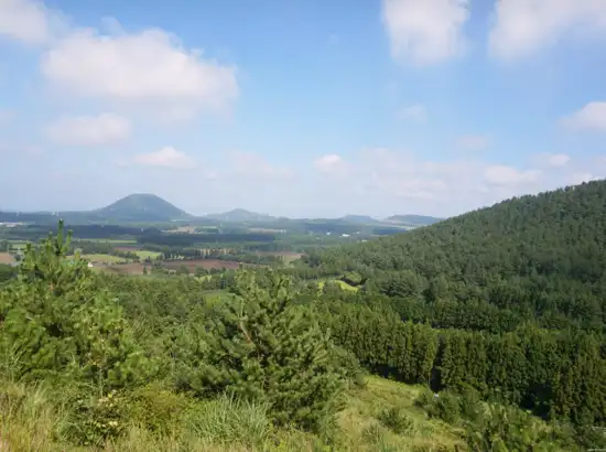 Panoramic landscape view of hills and fields near Jeju Gujwa Andol Oreum Secret Forest in South Korea.
