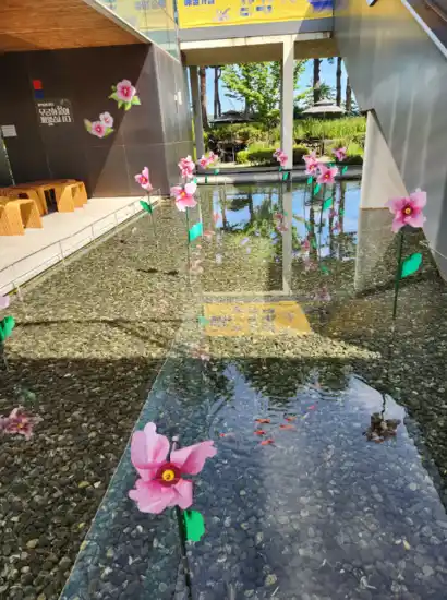 Water garden with pink flower installations reflecting sunlight at Mangu History Culture Park.