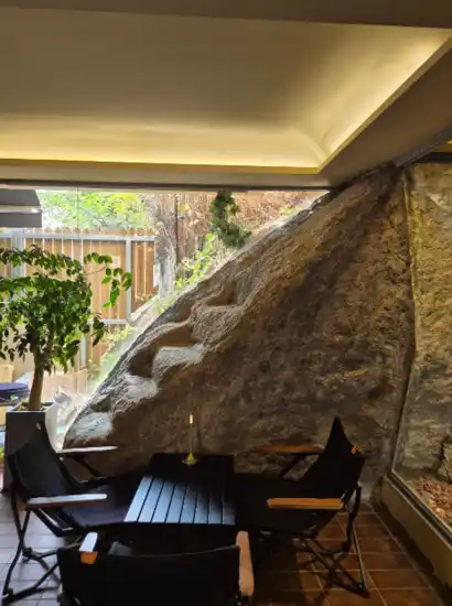 Indoor cafe space with a natural rock wall near Marronnier Park Seoul, featuring cozy seating and soft daylight.