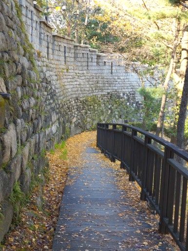 A quiet autumn walking trail along the stone fortress wall in Namsan Park, a scenic cultural heritage path in Seoul.