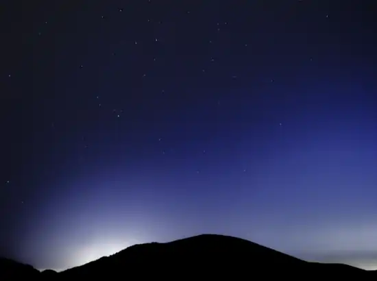 Night sky over Saebyeol Oreum with scattered stars and a dark hillside silhouette in Jeju Island.