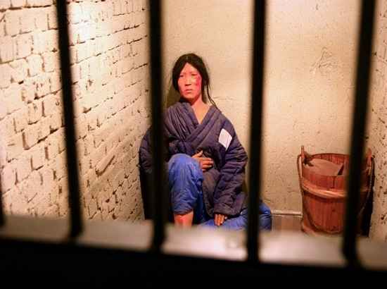 Exhibit of a solitary confinement cell at Seodaemun Prison History Hall showing a figure representing a female prisoner in harsh conditions.