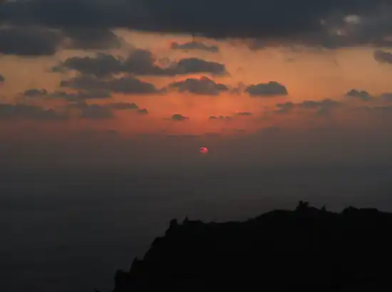 “Red sunrise above the ocean captured during a Seongsan Ilchulbong sunrise trip, showing the glowing sun and dramatic clouds over Jeju’s eastern coast.