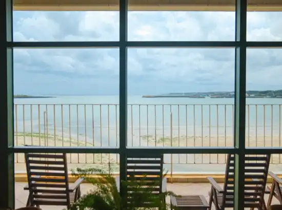 Oceanfront window view from Seogwipean Cafe during a Seongsan Ilchulbong sunrise trip, showing calm water, beach scenery, and relaxing chairs.