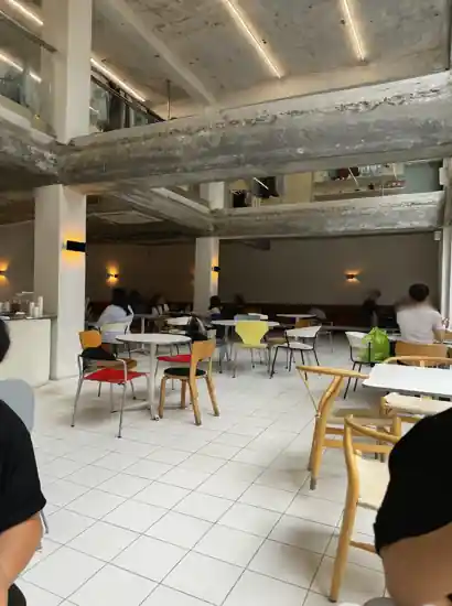 Interior of an industrial-style café in Seongsu, Seoul with open concrete beams and colorful chairs — Seongsu travel atmosphere.