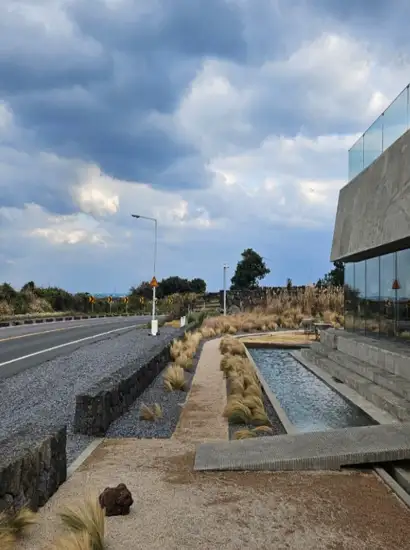 Seopjikoji travel scene showing a modern café beside a quiet Jeju roadside under a dramatic cloudy sky.