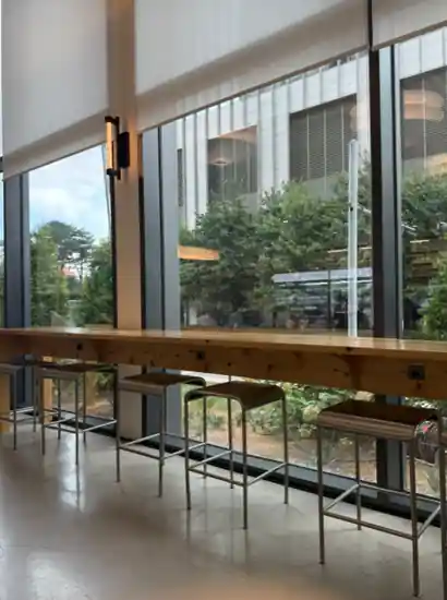 Calm café interior in Yeouido with high window seats, wooden counter, and a clear view of greenery outside.