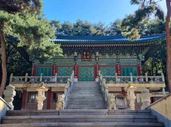 The main hall of Seonrimsa Temple along the Seoul Dulle-gil 17 Course, featuring traditional Korean wooden architecture and stone lanterns under a clear sky.