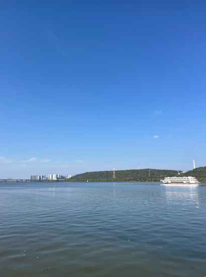 A clear river view along the Seoul Dulle-gil 14 Course Anyangcheon Downstream, featuring a blue sky and a white sightseeing boat on the water.