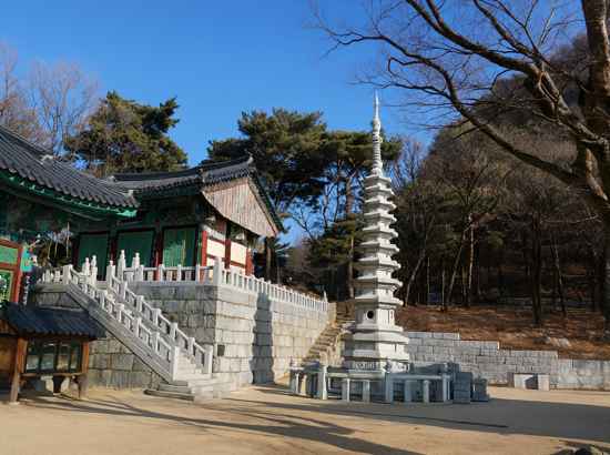 Hoapsa Temple and a tall stone pagoda along Seoul Trail 12 Hoamsan on a clear sunny day.