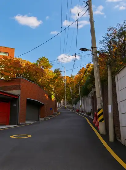 Uphill residential street with light autumn foliage on the Seoul Trail 18 Course