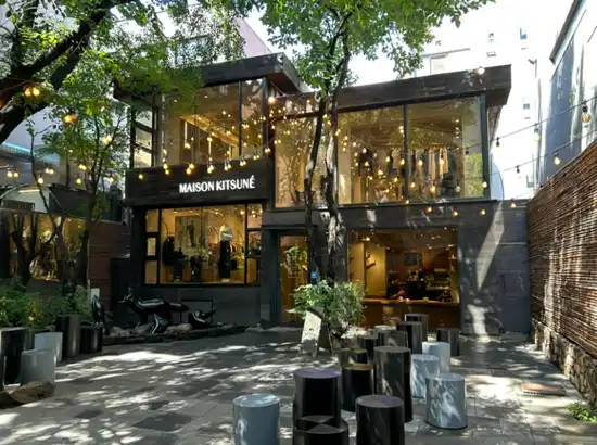 A stylish courtyard view of Maison Kitsuné in Seoul, featuring warm lights and modern seating, captured for the Sillim date course itinerary.