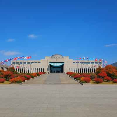 The War Memorial of Korea in Seoul under a vivid blue sky, surrounded by autumn-colored trees representing peace and remembrance.