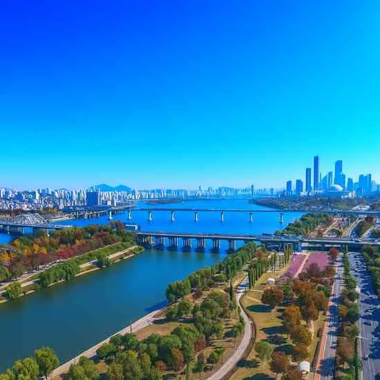 A clear panoramic view of Yanghwa Hangang Park and the Han River in Seoul, featuring bright blue skies, bridges, and the city skyline.
