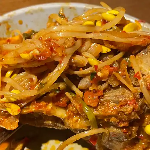 Close-up of a spicy braised dish from Dongbaekgaok, featured in the Yeonnam-dong One-Day Course, with tender meat, bean sprouts, and rich red seasoning.