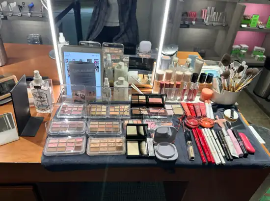 Table of makeup products and tools prepared for the Amore Seongsu K-Beauty Makeup Class, featuring eyeshadow palettes, brushes, lip products, and skincare items.
