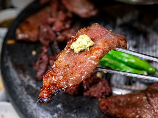 apgujeong food – grilled hanwoo beef bite held with chopsticks over the grill