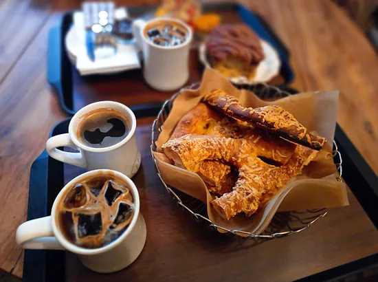 Iced coffee and hot coffee served with flaky pastries on a tray during an Apgujeong Rodeo cafe tour