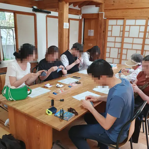 Bukchon Traditional Craft Experience group workshop in a Korean hanok, foreign visitors learning traditional craft techniques together