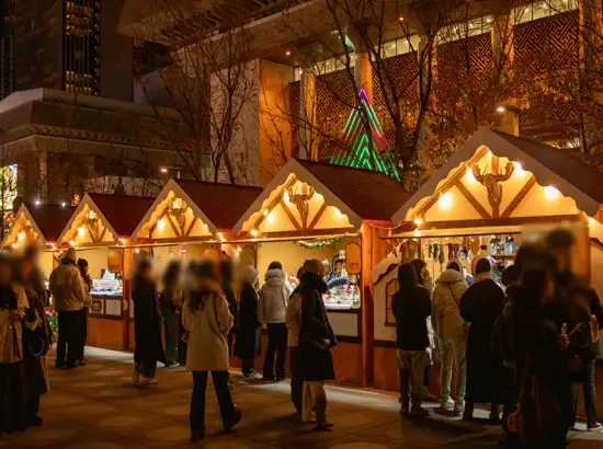 Visitors standing in line at wooden street stalls at Gwanghwamun Market during the Seoul Winter Festival, illuminated with warm lights at night.
