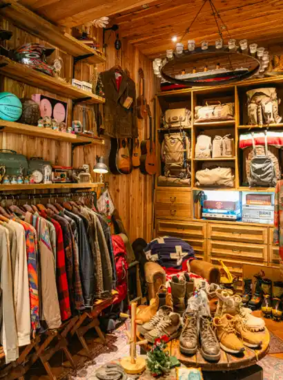 Warm vintage-style interior of a Jeju cafe often visited after Hallasan Dongbaek-gil trekking, featuring wooden shelves, retro clothing, guitars, and rustic decor.