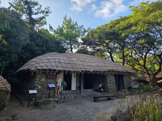 A traditional thatched stone house at Jeju Folk Village, showing the historic rural lifestyle included in the Jeju Folk Village entrance fee experience.