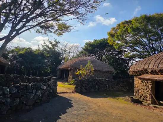 Traditional stone-wall houses inside Jeju Folk Village, showing authentic rural culture included in the Jeju Folk Village entrance fee experience.