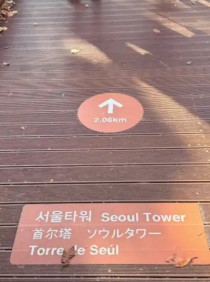 Direction marker on the boardwalk showing “Seoul Tower” and distance, useful for namsan sky forest trail wheelchair access planning