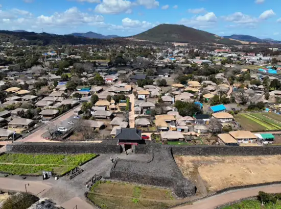Aerial view of Seongeup Folk Village showing rows of traditional thatched roof houses and stone walls in Jeju, Korea