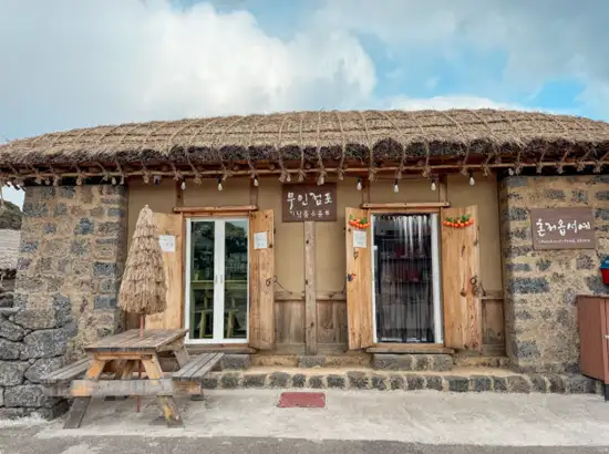 Traditional stone and thatched roof store at Seongeup Folk Village displaying an unmanned gift shop exterior in Jeju, Korea