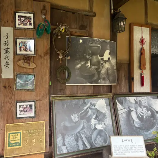 Traditional cultural exhibit inside Seongeup Village Traditional House showing historical images and craft items in Jeju