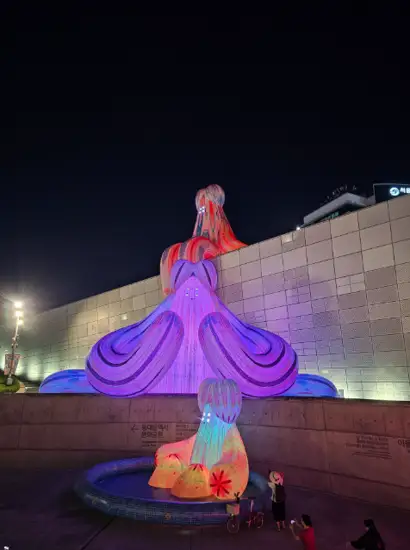 Colorful illuminated sculpture installed at Seoul Light DDP at night, featuring vibrant digital projection and visitors admiring the artwork.
