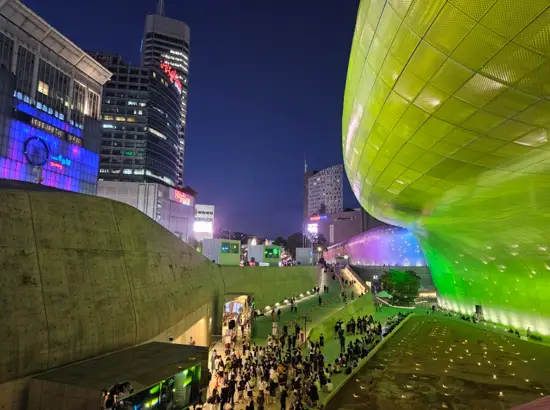 Night view of Seoul Light DDP with illuminated media facade and visitors enjoying the winter festival at Dongdaemun Design Plaza.
