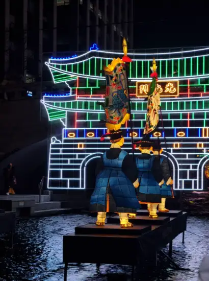 Traditional guard lantern figures displayed during Seoul Light Gwanghwamun festival in front of illuminated gate installation at night