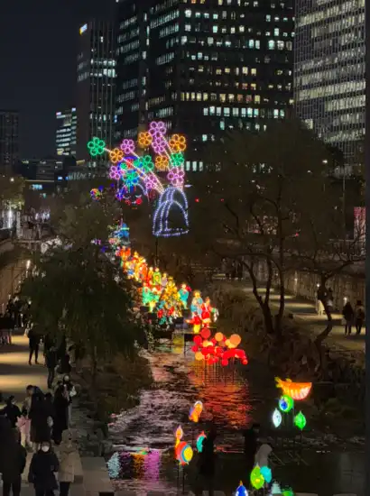 Night view of the Cheonggyecheon Light Festival during the Seoul Winter Festa, featuring glowing lantern installations along the stream.