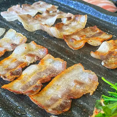 Samgyeopsal grilling on a hot plate at Sinsa Gyoja Naengsam, an Apgujeong budget restaurant