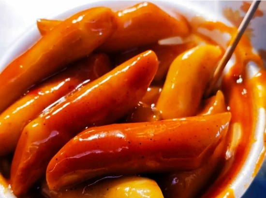 myeongdong street food night market tteokbokki (spicy rice cakes) close-up in red sauce