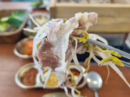 Beef and fresh vegetables lifted with chopsticks at Bangi Pyeonbaek Yukbunsamsip Yeouido Main Branch in Seoul.