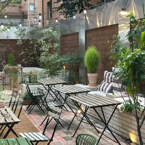 Outdoor terrace at Bittersalt Cafe with tables and chairs, string lights, and potted trees arranged harmoniously
