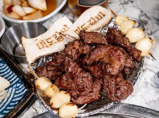 LA galbi on a plate at Mido Galbi, served with grilled garlic skewers and mushrooms.
