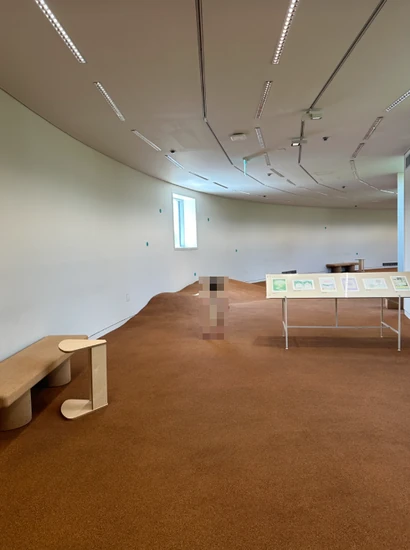 A curved, gently sloped rest area where kids can play and take a break in an open gallery space.