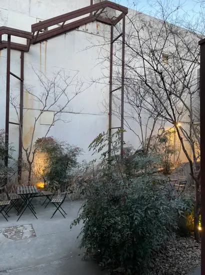Outdoor garden seating area at Onion Seongsu with trees, concrete walls, and small café tables